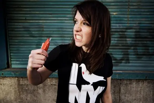 A music producer holding a knife in front of a wall.