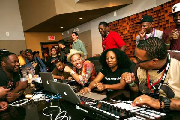 A group of music producers sitting around a table with laptops, engaged in beatmaking and free online music production.
