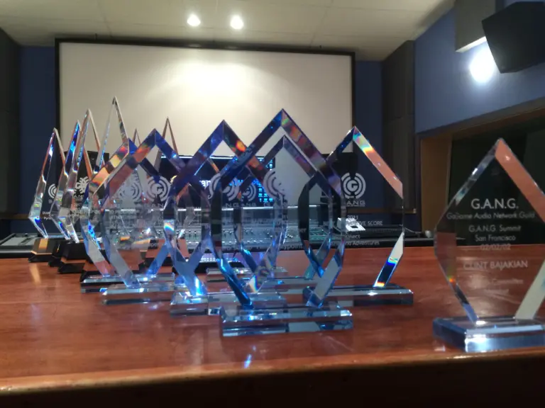A group of music producer awards on a table in front of a wooden desk.