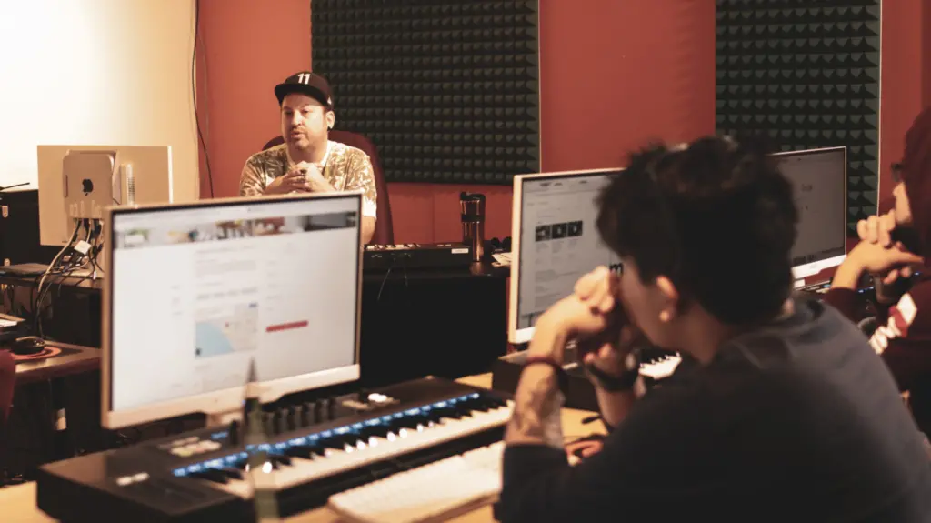 A group of people engaged in beatmaking and music production program in a recording studio.