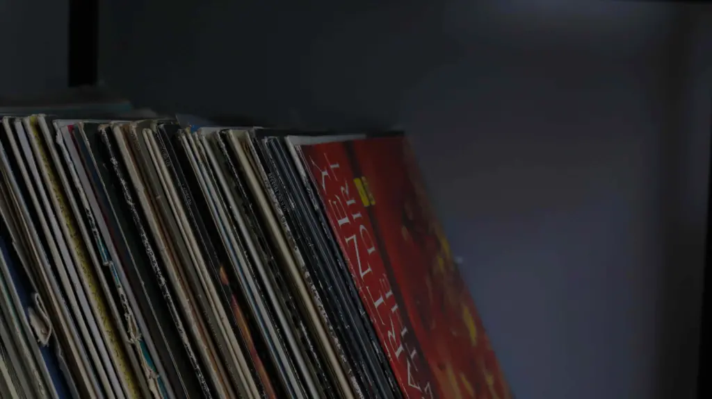 A stack of vinyl records on a shelf, perfect for music production program lovers.