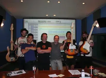 A group of people posing with guitars in a recording studio, engaging in beatmaking and using music producer program.